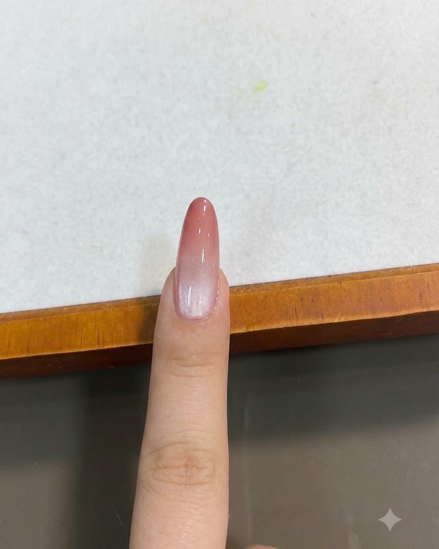 Ein fertiger Pfirsich-Rosa-Farbverlauf-Cat-Eye-Nagel aus einer Nahaufnahme von oben.