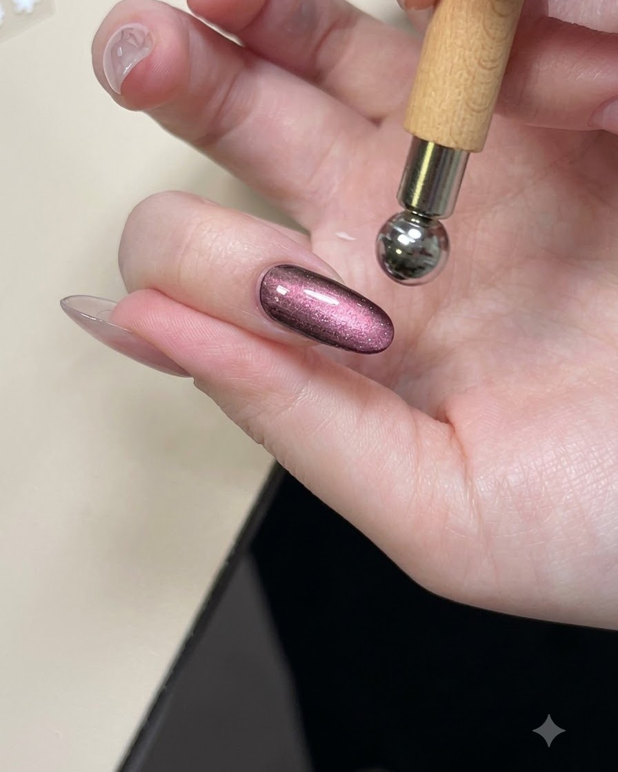 Ein Magnetwerkzeug wird über einen glänzenden lila Cat-Eye-Nagel gehalten, um den Schimmer zu formen.
