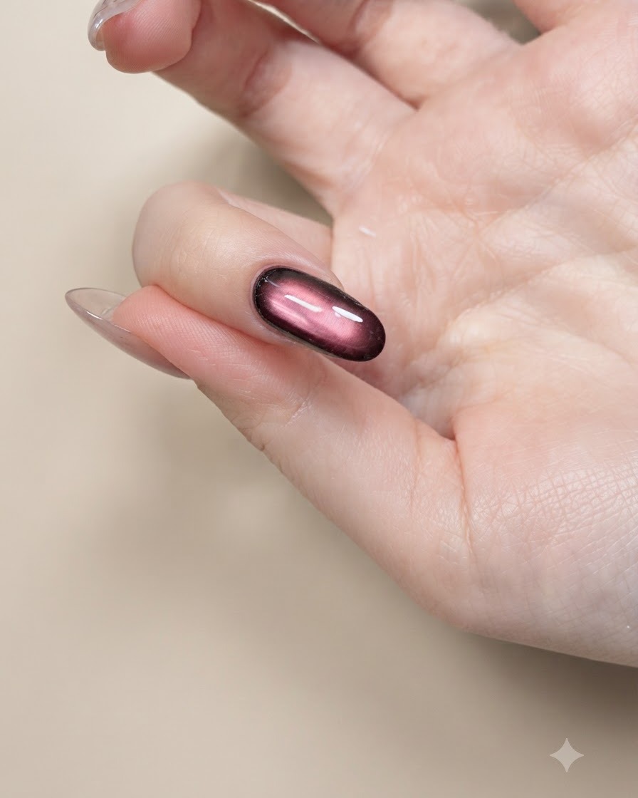 Ein feiner Nail-Art-Pinsel malt schwarze Schmetterlingsflügel-Umrisse auf einen Nude-Nagel.