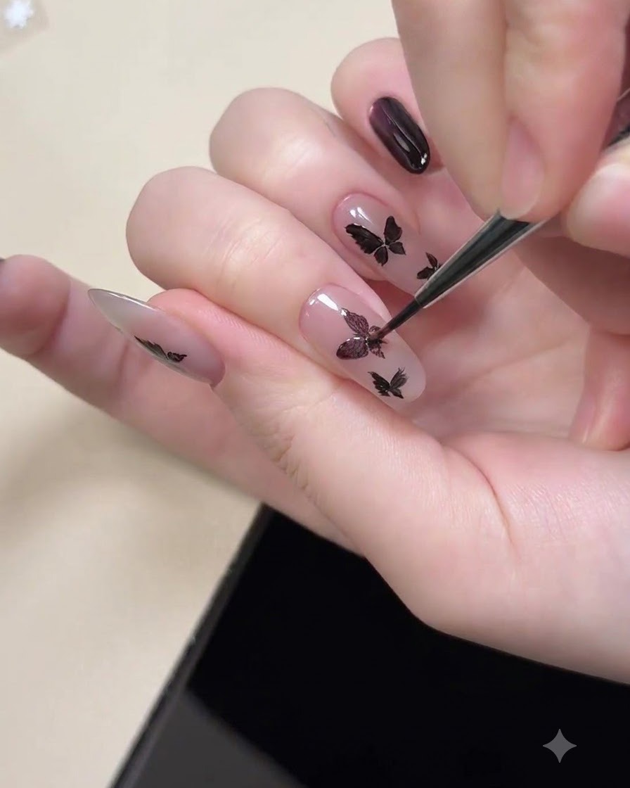 Ein Magnetwerkzeug wird in der Nähe eines Fingernagels gehalten, um den lila Cat-Eye-Schimmer innerhalb gemalter schwarzer Schmetterlingsformen zu magnetisieren.