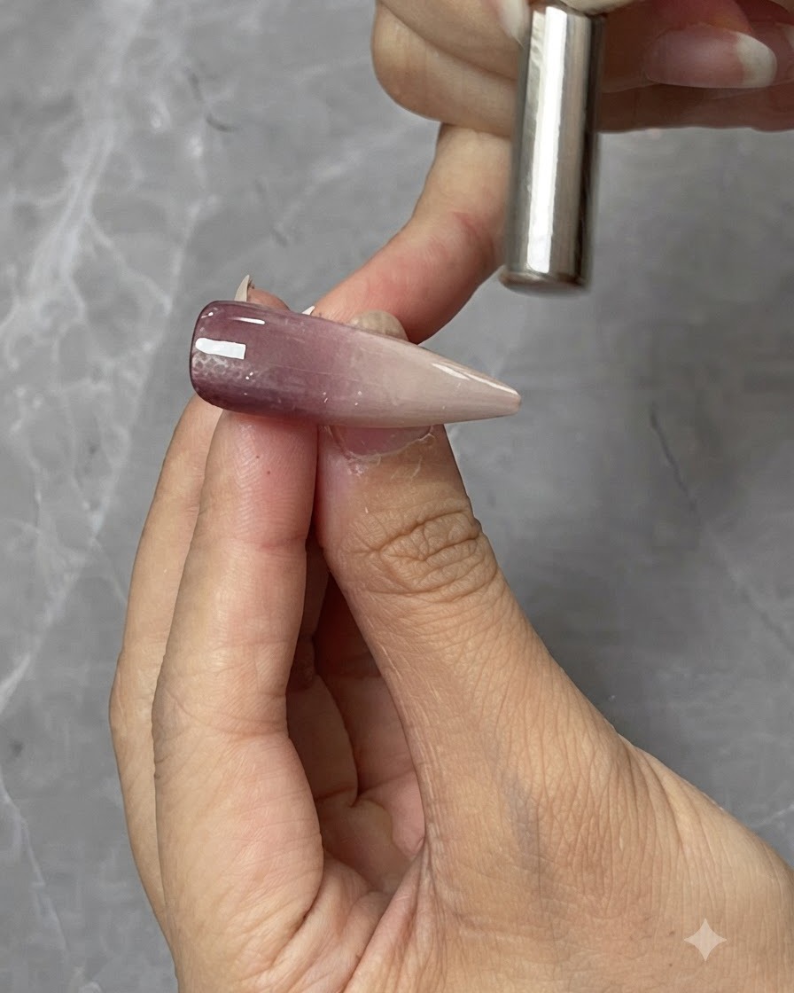 Ein zylindrischer Magnet wird knapp über einer Cat-Eye-Gel-Nagelspitze gehalten, um die magnetische Lichtreflexion zu formen.