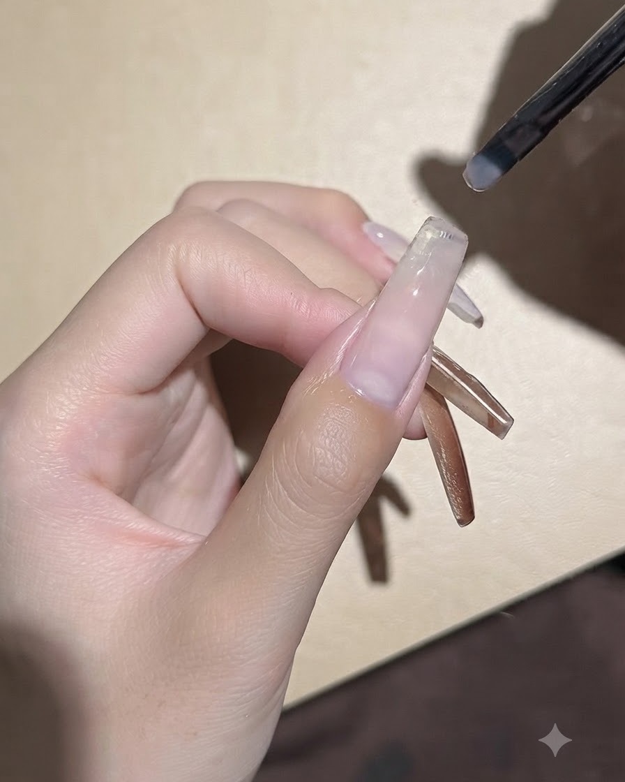 Ein kleiner Gelpinsel trägt eine glatte Schicht klares Base-Gel auf eine vorbereitete Nagelplatte auf.