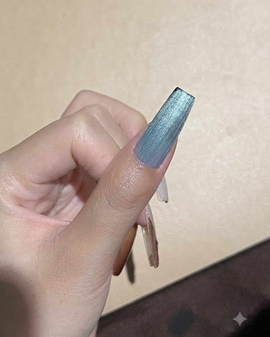 Ein starker Magnet wird nah an einen blauen Cat-Eye-Gel-Nagel gehalten, um die Lichtreflexionslinie zu verfeinern.