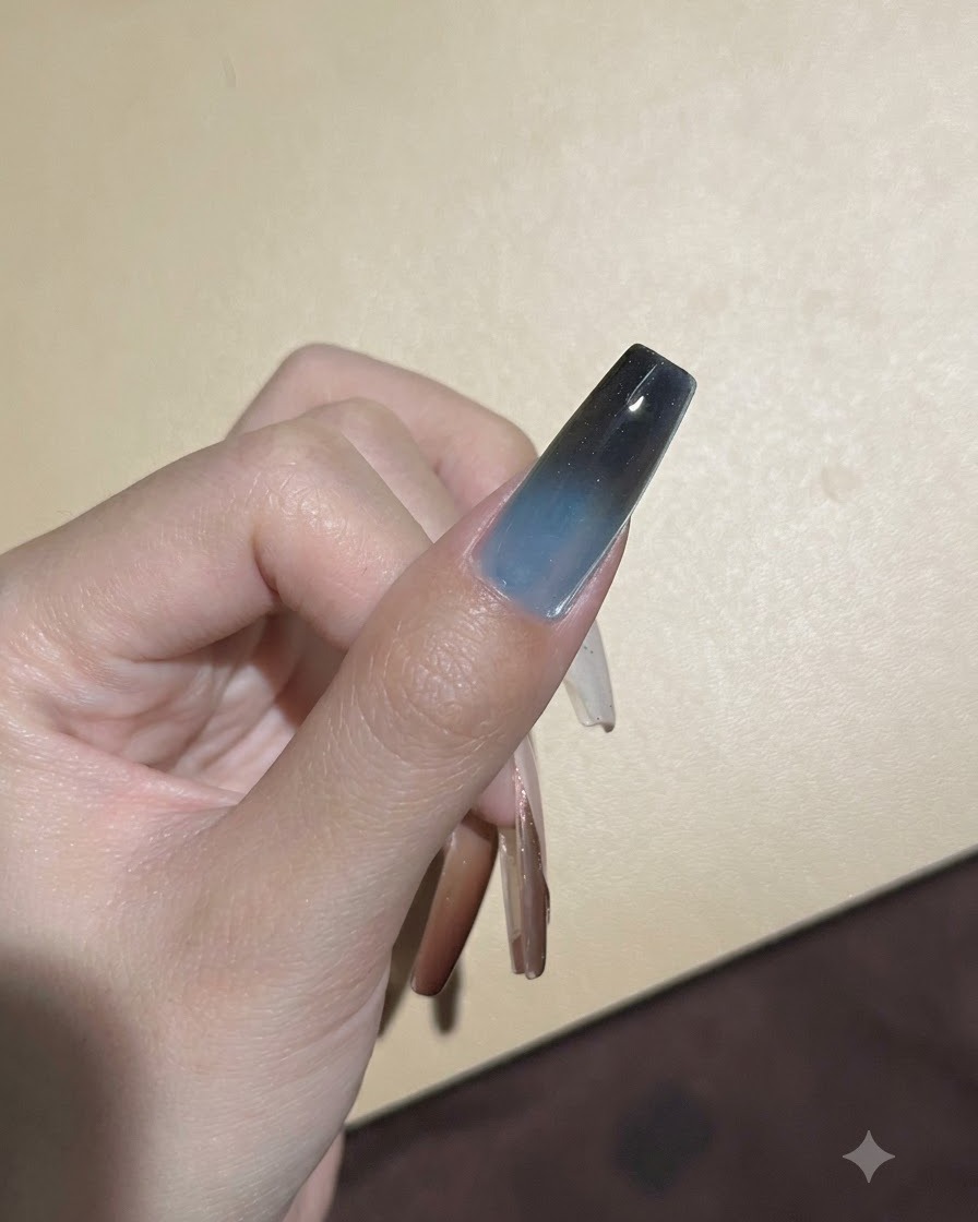 Ein Schwamm tupft dunkles Pigment auf die obere Spitze eines Gel-Nagels, um den Ombré-Übergang zu vertiefen.