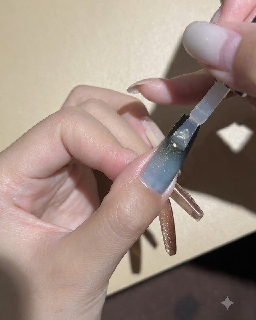 Ein Nagelpinsel trägt einen klaren, glänzenden Top-Coat über dem dunklen Farbverlauf und dem Cat-Eye-Gel-Nagel auf.