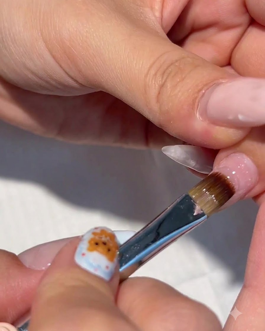 Eine Nahaufnahme eines Pinselns, der klaren Aufbaugel auf einen vorbereiteten Fingernagel aufträgt.