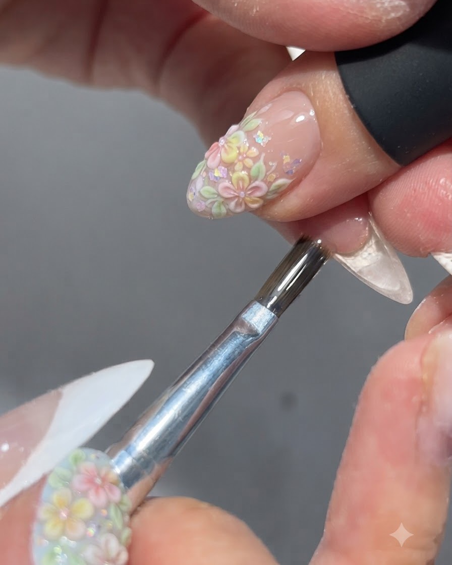 Ein Pinsel trägt einen glänzenden Top-Coat über ein fertiges florales Nageldesign auf.