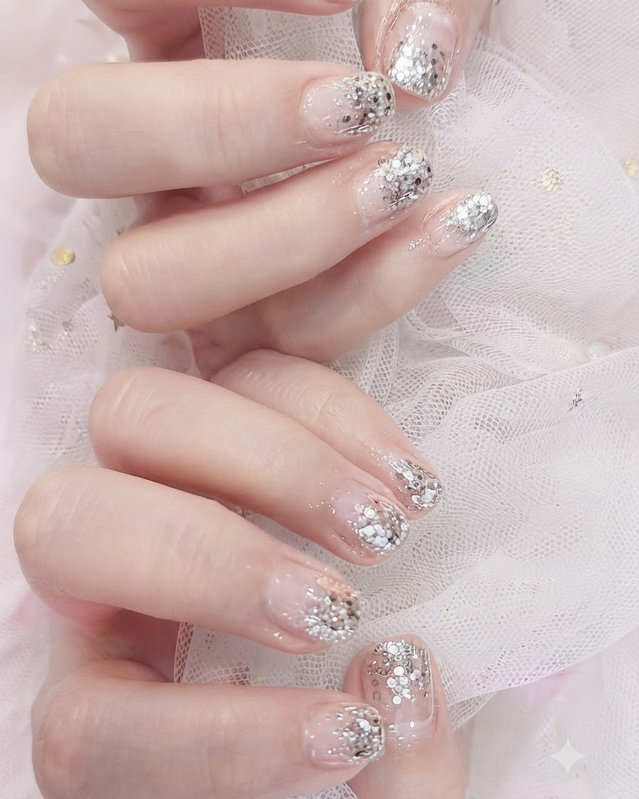 Ein Gel-Pinsel trägt eine transparente Nude-Rosa-Farbe auf einen Fingernagel auf.