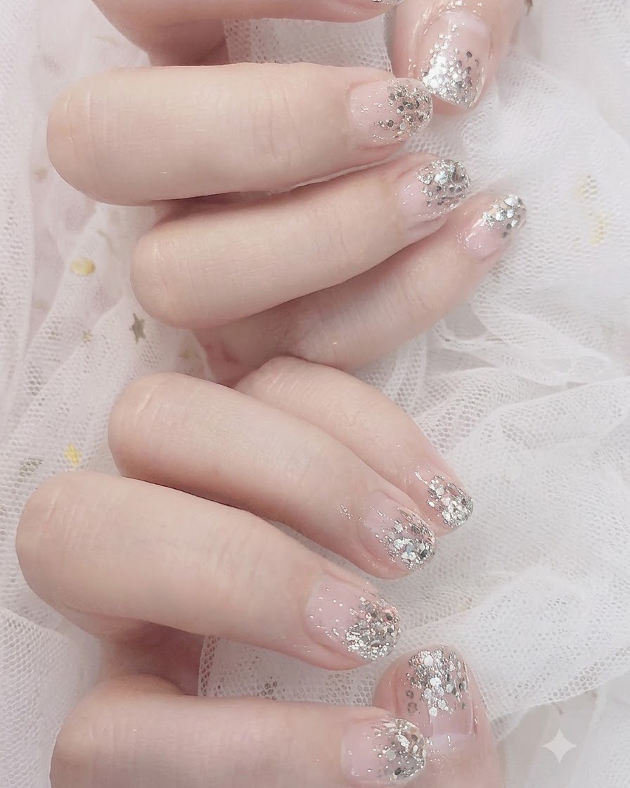 Detailaufnahme von silbernem Glitzer-Gel, das mit Schwamm und Pinsel auf die Nagelspitzen getupft wird, um einen Ombre-Effekt zu erzielen.