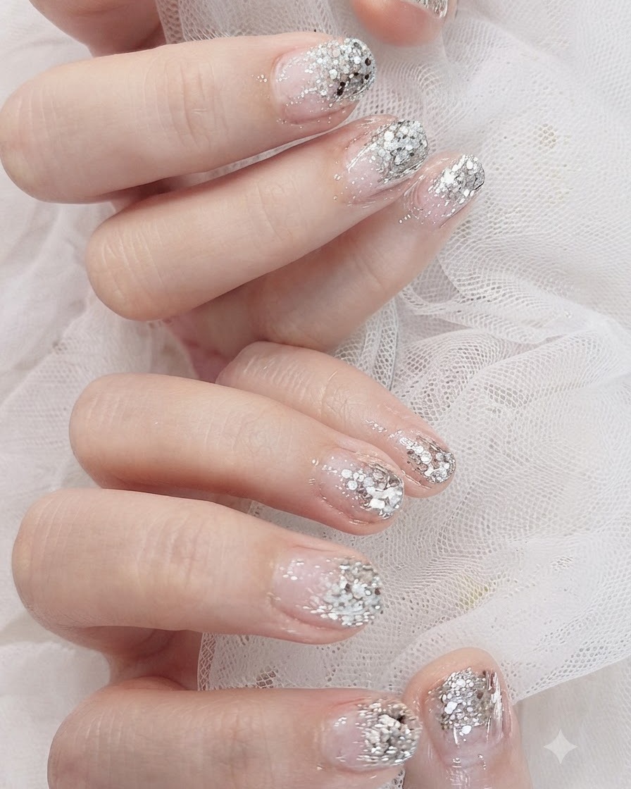 Nahaufnahme mit konzentrierten silbernen Glitzerflocken, die den Nagelspitzen für einen tieferen Farbverlauf hinzugefügt werden.
