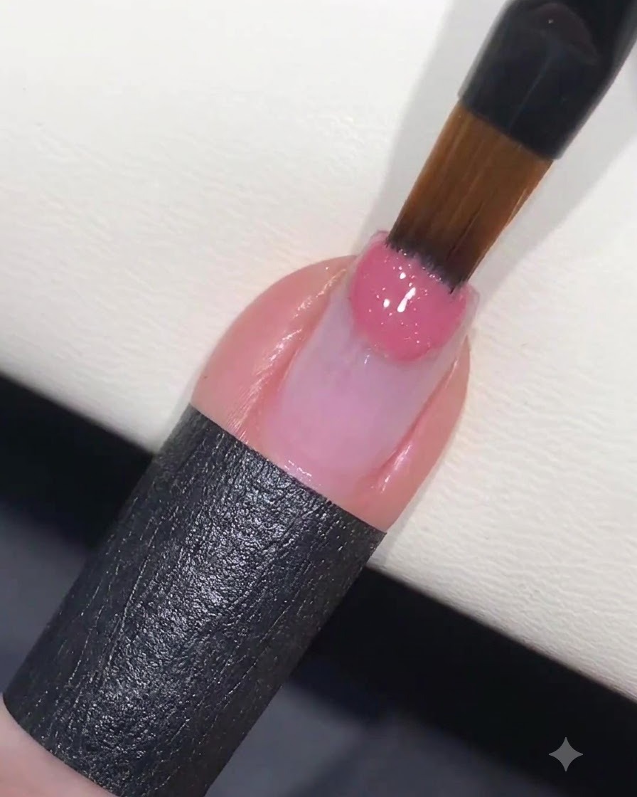 Ein Nagelpinsel, der rosa Farbgel auf die Spitze eines vorbereiteten Fingernagels aufträgt.