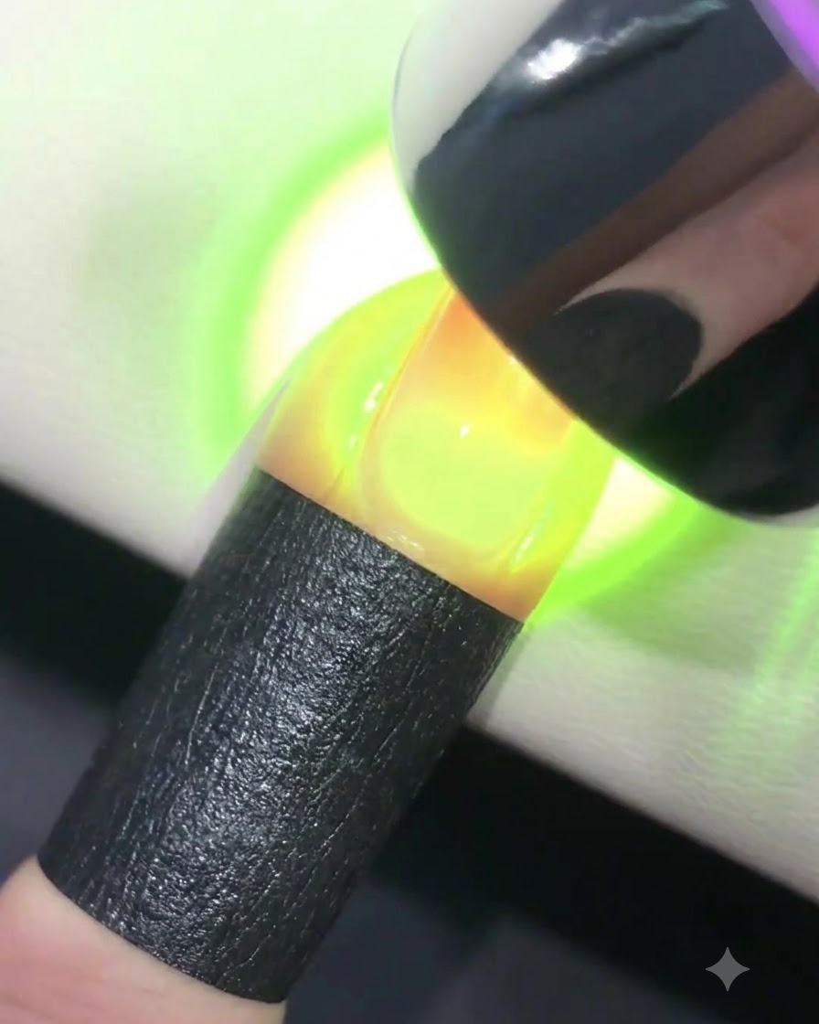 Ein Finger, der unter einer leuchtenden UV- oder LED-Lampe aushärtet.
