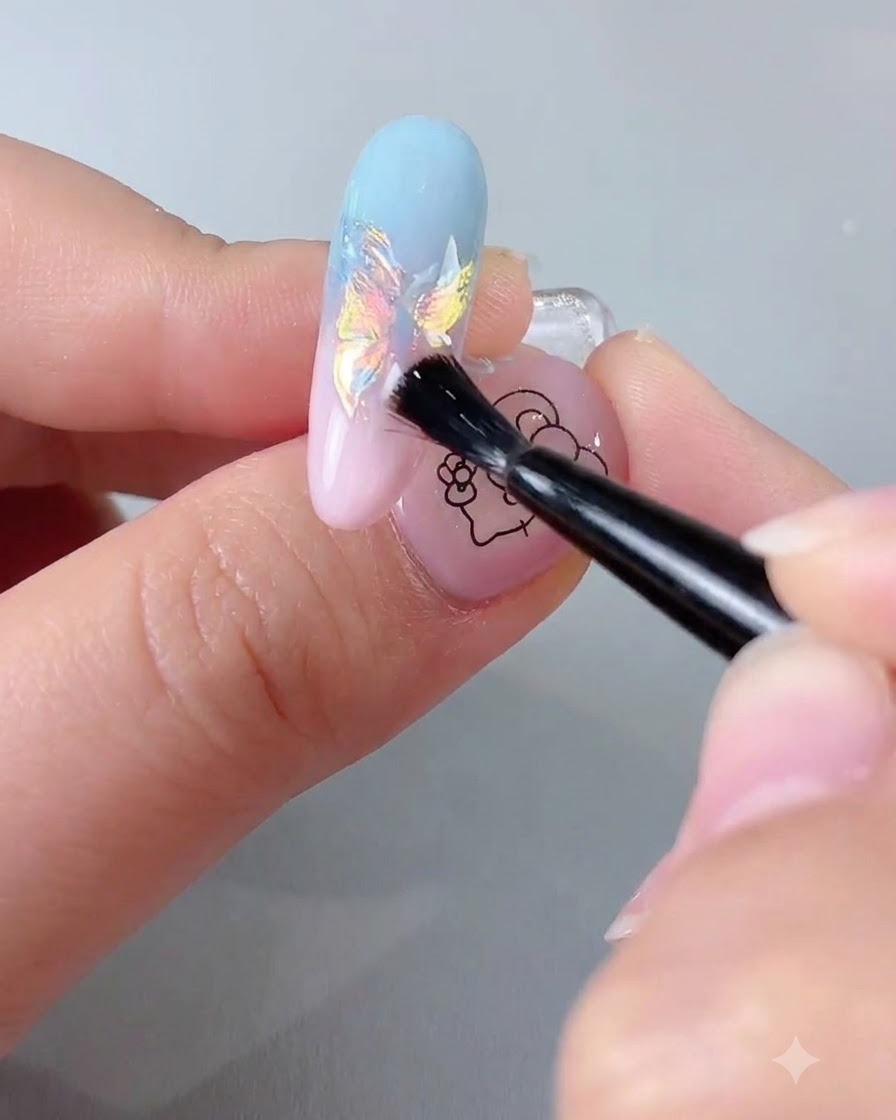 Ein Nagelpinsel trägt einen klaren, versiegelnden Top Coat über eine irisierende Chrom-Nagelverlängerung auf.