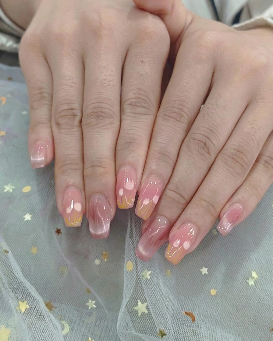 Ein Ombré-Pinsel verblendet sanft pinkes und gelbes Gel-Polish in der Nagelmitte.