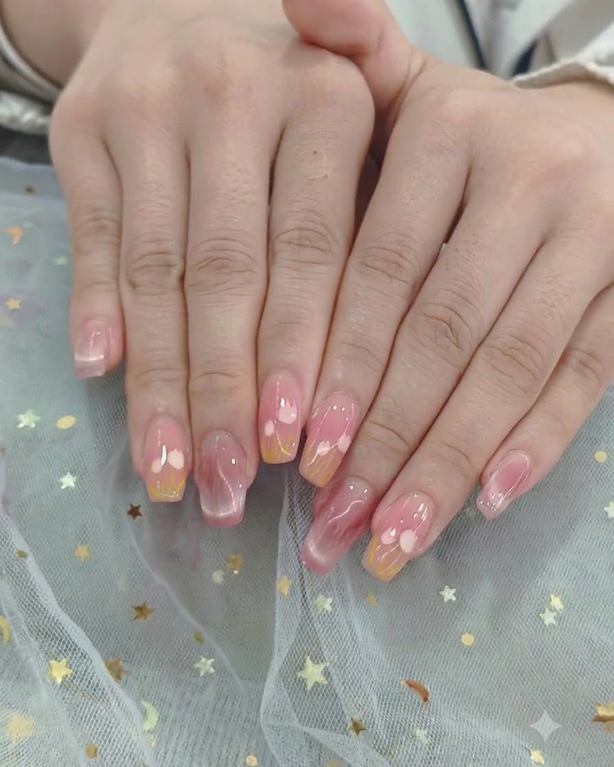 Ein Pinsel zieht einen glänzenden Top Coat über ein fertiges Herz- und Ombré-Nageldesign.