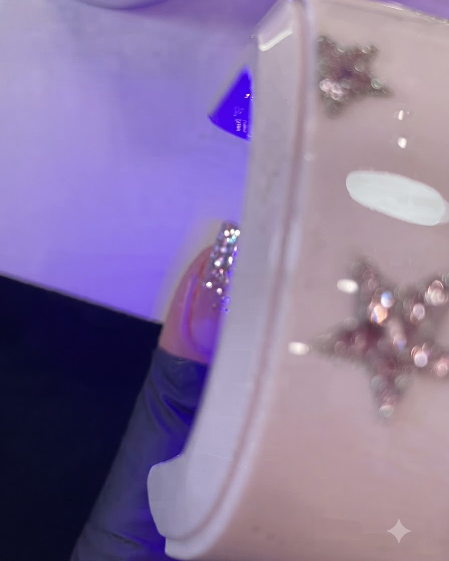 Nahaufnahme eines Fingers mit nassem Gel, das unter einer lila Mini-UV/LED-Lampe ausgehärtet wird.
