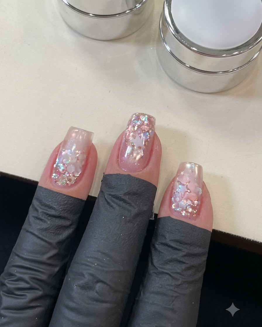 Eine Nahaufnahme einer Hand, die Top Coat über die detaillierte Stern- und Pailletten-Nail-Art aufträgt.