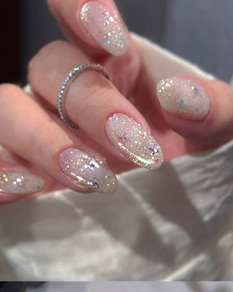 Ein Nagelpinsel trägt eine gleichmäßige Schicht transparentes Nude-Rosa-Gel auf einen Naturnagel auf.