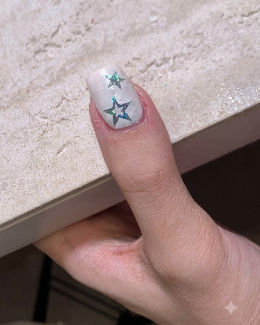 Ein Fingernagel mit Sternstickern befindet sich unter einer kleinen, tragbaren LED-Aushärtungslampe.