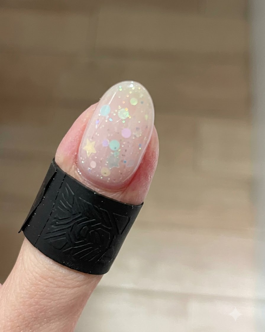 Eine Nahaufnahme eines Fingernagels mit einem leuchtenden Cat-Eye-Gel-Effekt, wobei sich der helle Schimmer über Stern-Glitzern auf die Spitze konzentriert.