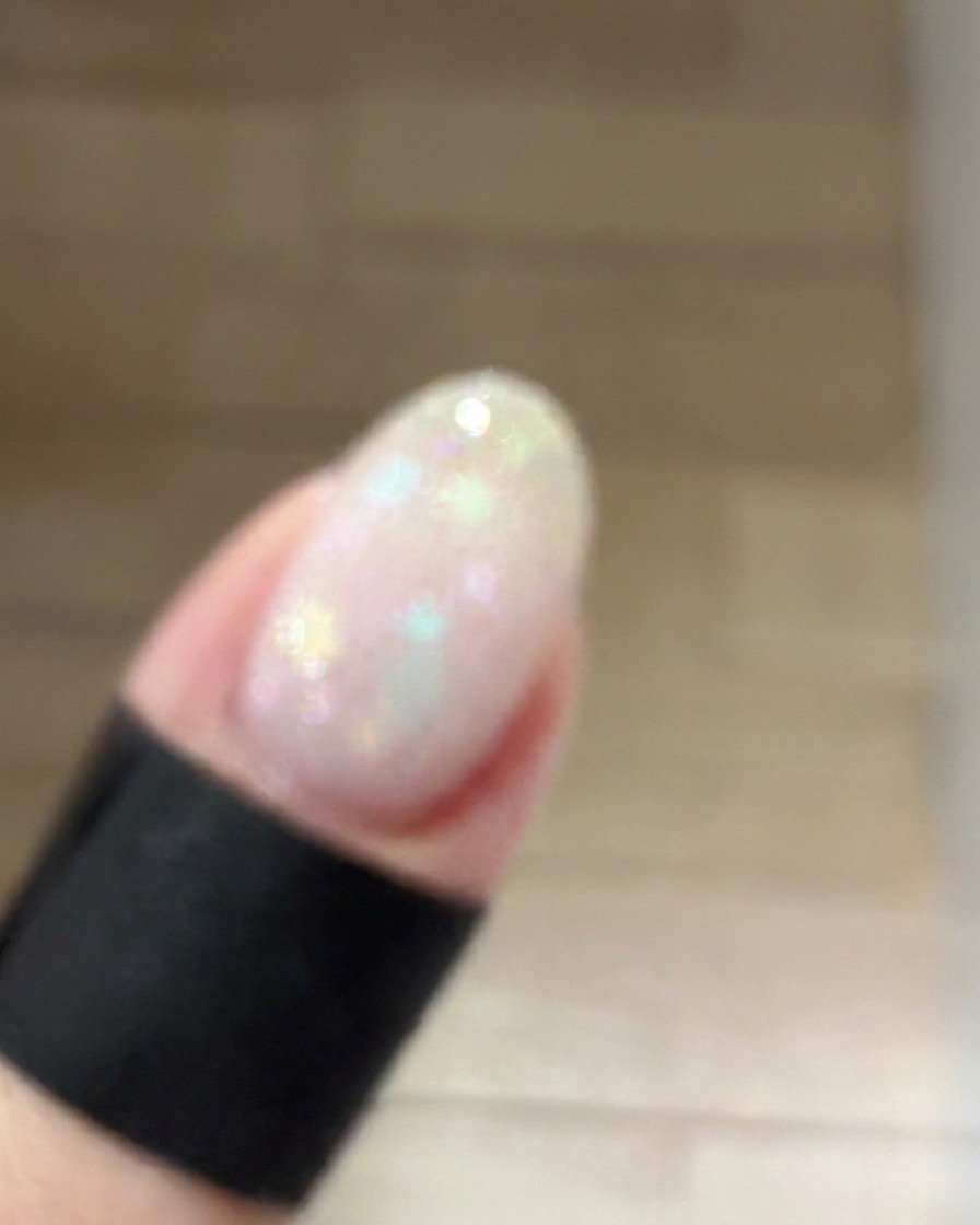 Ein kleiner Make-up-Schwamm tupft sanft staubrosa Gel auf die Mitte eines manikürten Nagels, um einen sanften Blush-Verlauf zu erzeugen.