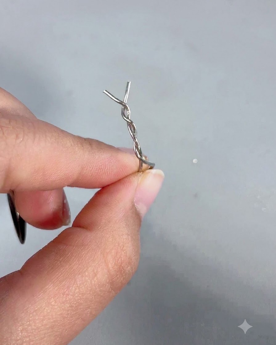 Eine Hand hält einen Magnetstab, an dessen Spitze eine verdrehte Haarnadel aus Metall befestigt ist.