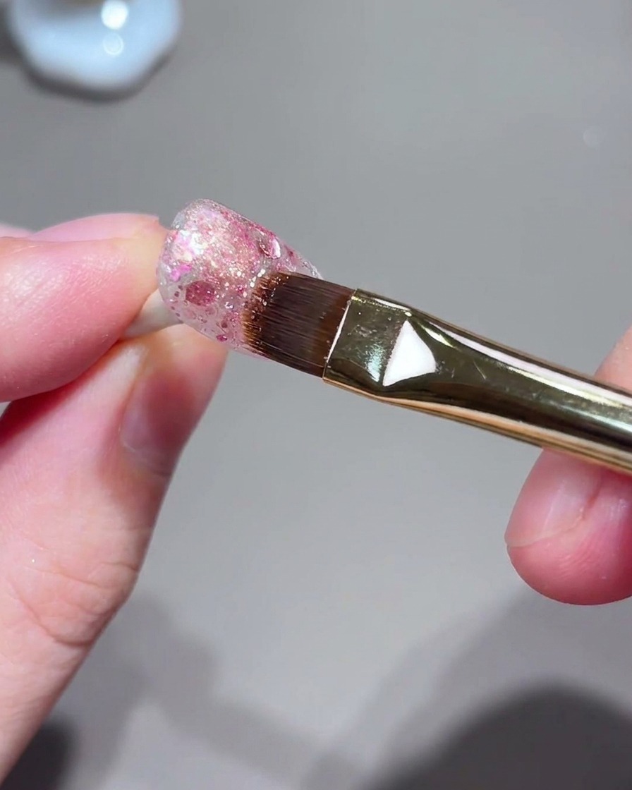 Ein Pinsel und Nagellayout während des magnetischen Bündelungsprozesses des Cat-Eye-Lichts.