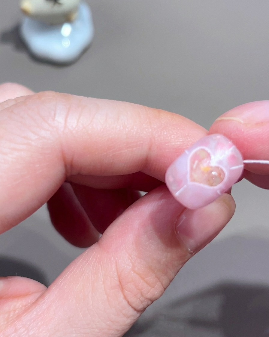 Nahaufnahme eines Nagels mit feinen weißen radialen Linien, die von einer zentralen Herzform nach außen verlaufen.