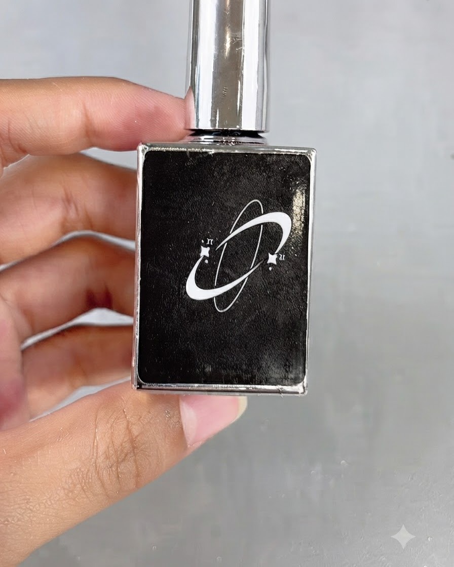 Eine schwarze Kosmetikflasche mit einem Planeten-Logo in der Hand.