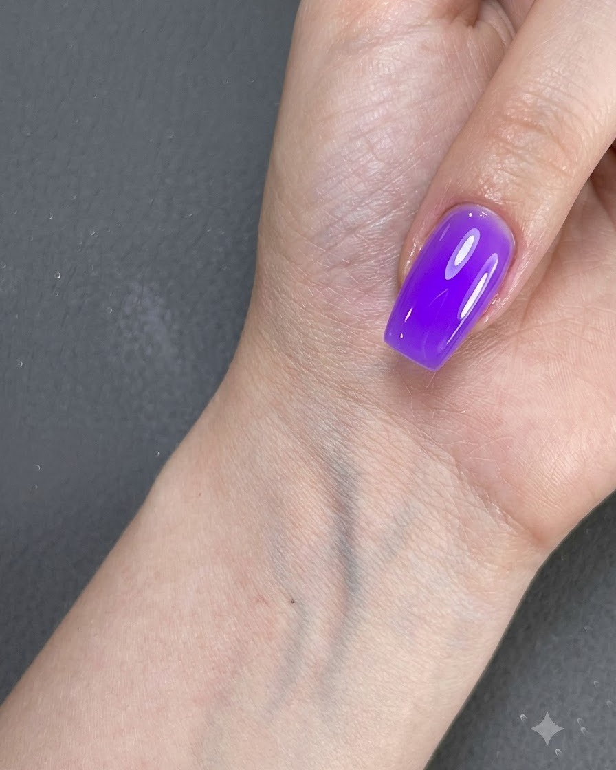 Eine Hand mit einem violett lackierten Nagel ruht nahe einer Oberfläche unter Beleuchtung.