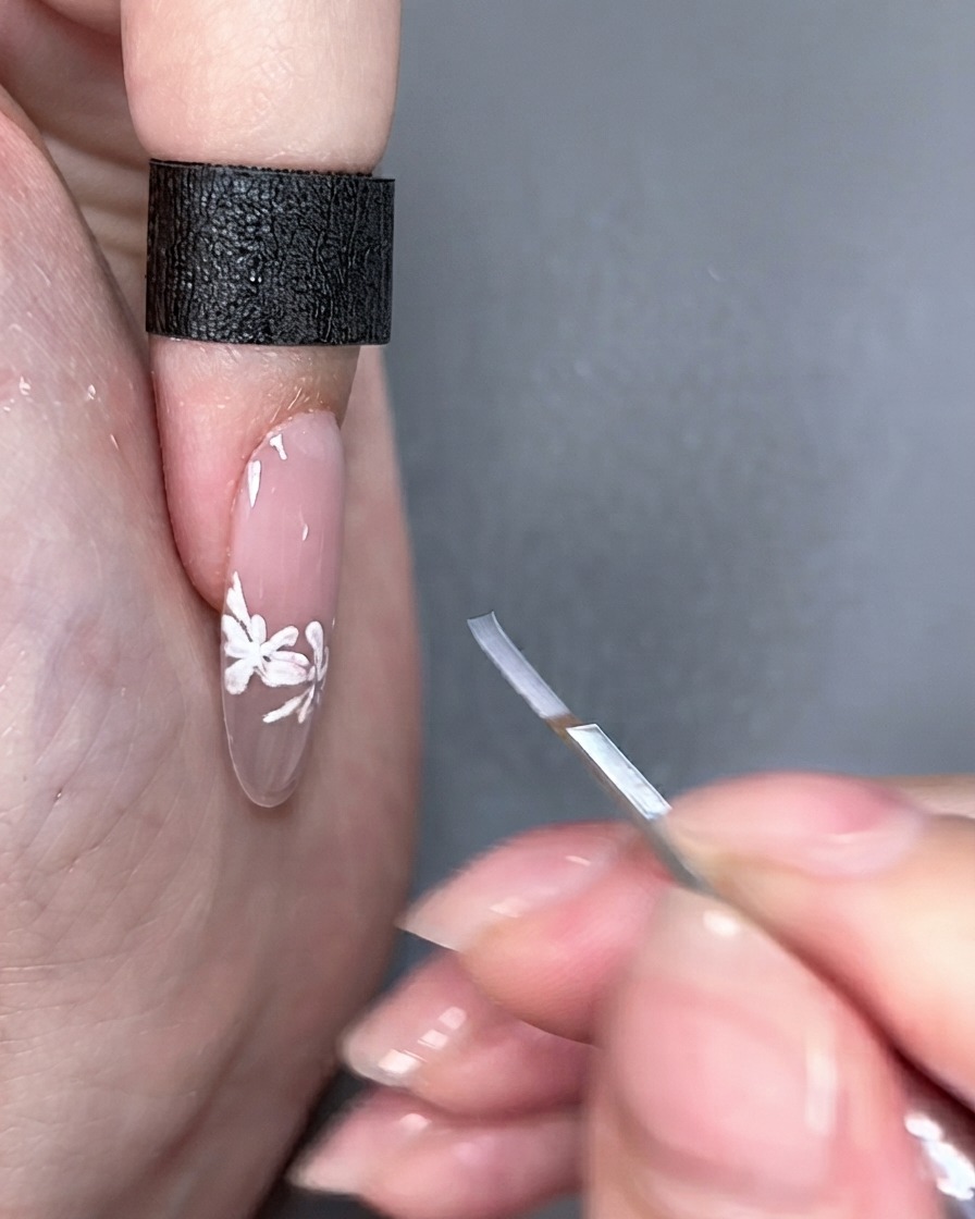 Ein Nail-Art-Pinsel wird neben einem fertigen Fingernagel unter Studiobeleuchtung gehalten.