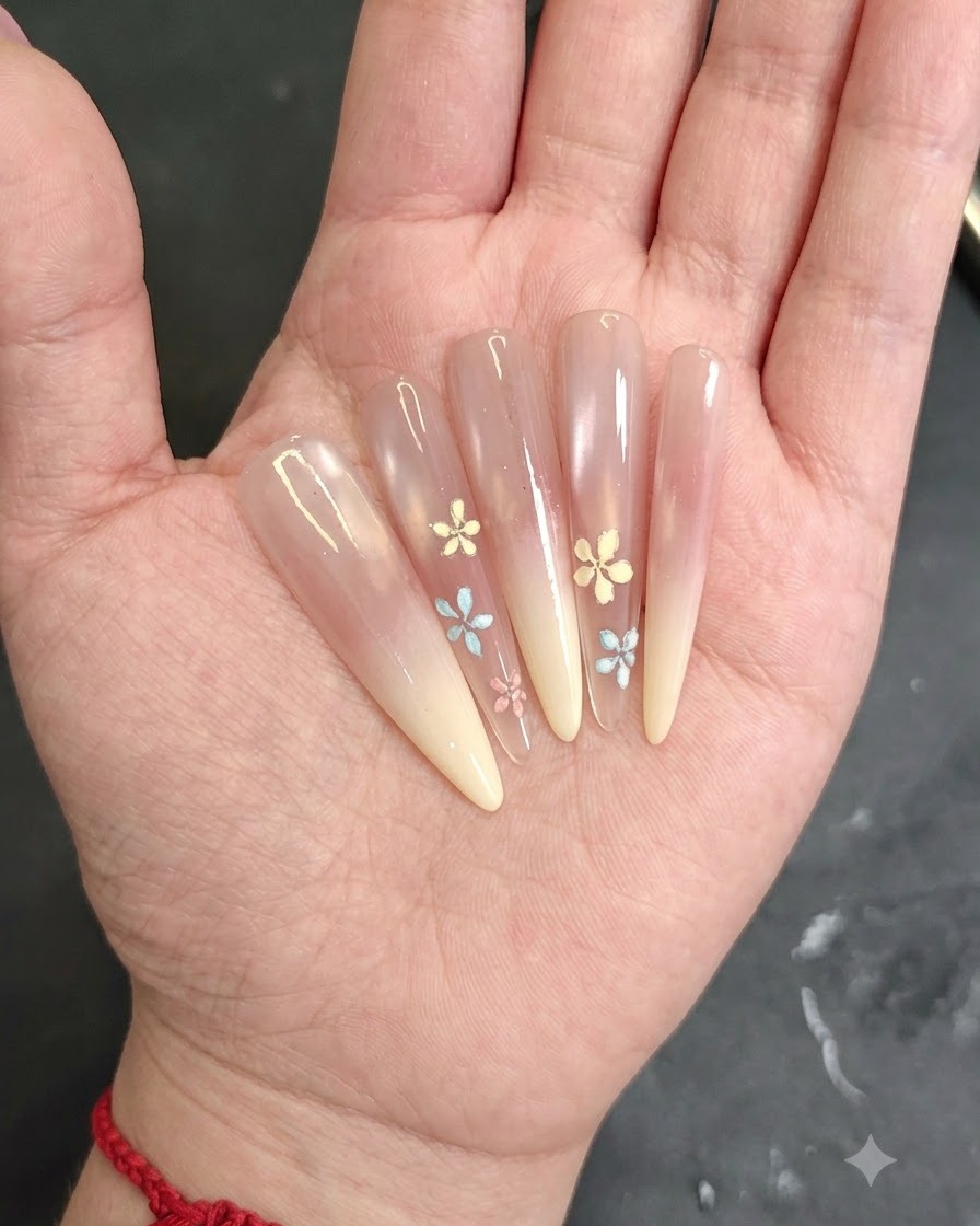 Eine Nahaufnahme einer Hand beim Auftragen von rosa Blush-Gel auf die Nagelspitze eines mandelförmigen Nagels.
