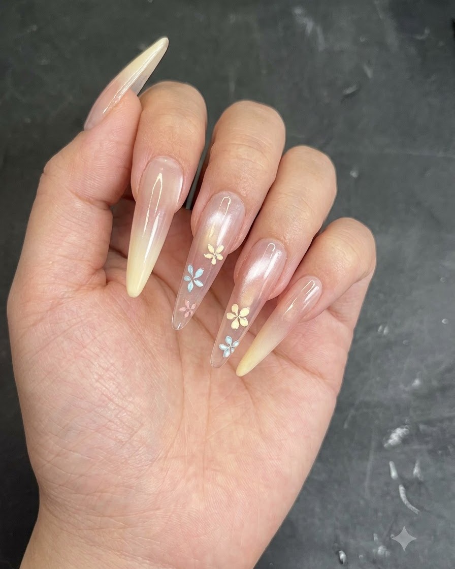 Ein Pinsel oder Schwamm tupft cremefarbenes Gel auf die Spitze eines klaren mandelförmigen Nagels für einen Ombré-Verlauf.