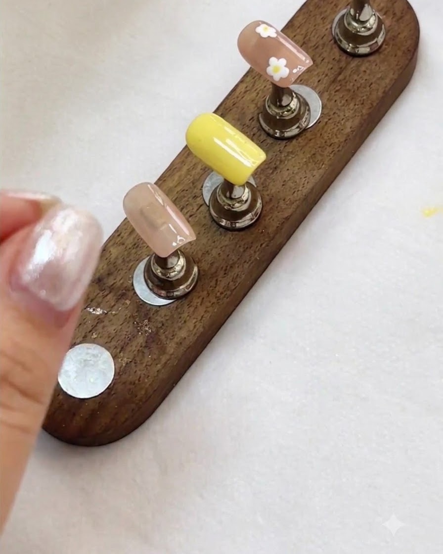 Ein Nageldisplay zeigt fertige florale und Nude-Nageldesigns, bereit für den nächsten Schritt.