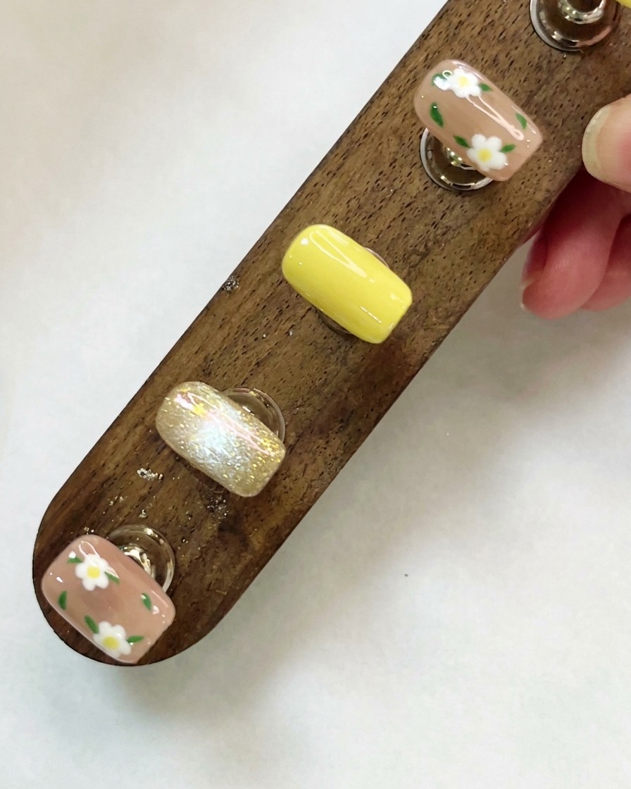 Ein Holzdisplayständer mit individuell gestalteten Nagelspitzen von oben betrachtet.