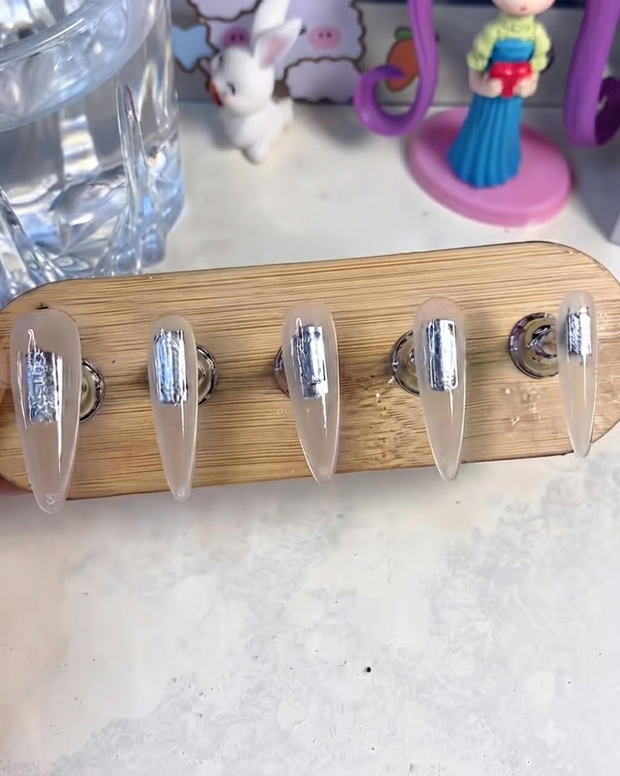 Ein Nagelständer mit fünf künstlichen Nägeln im Inneren einer UV- und LED-Härtungslampe, um die Base-Gel-Schicht auszuhärten.