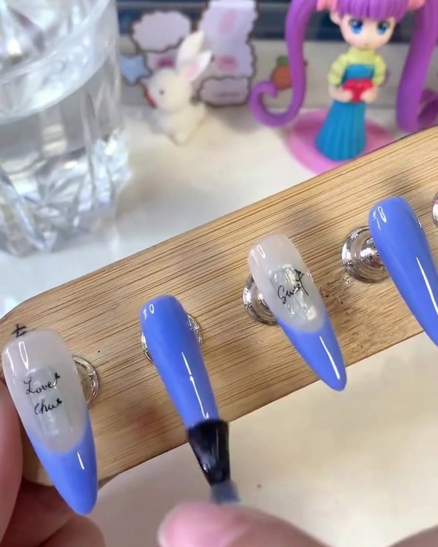 Ein Pinsel trägt matten Top Coat gleichmäßig über die Oberfläche der lackierten Nägel auf einem Holzständer auf.