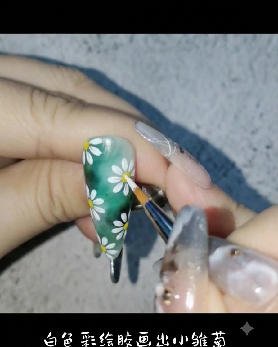 Ein Liner-Pinsel verwendet weißes Malgel, um zarte Gänseblümchenblätter auf den grünen Nagelgrund zu zeichnen.