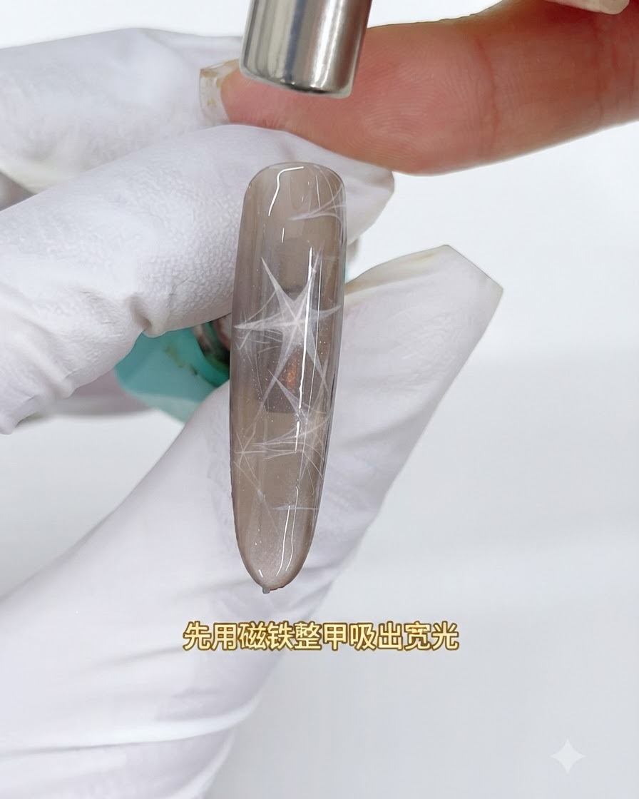Ein zylindrischer Magnet schwebt über einem braunen Cat-Eye-Nagel, um ein breites reflektierendes Lichtband herauszuziehen.