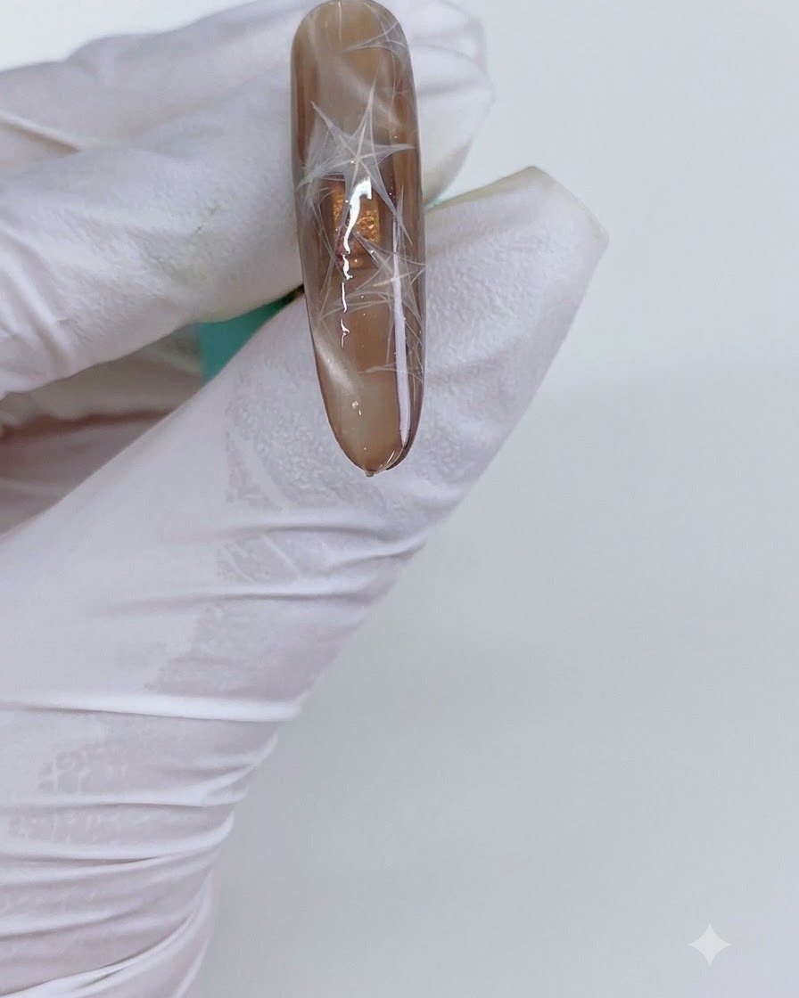 Ein manikürter Nagel mit Cat-Eye-Dreiecken wird unter eine Aushärtungslampe gelegt.