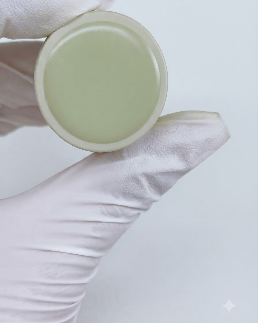 Ein Glas M13 Cat-Eye-Gel wird neben einer behandschuhten Hand hochgehalten.