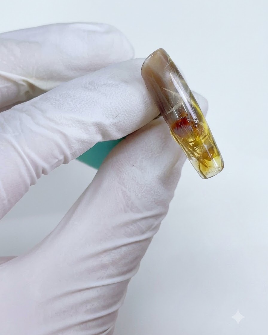 Ein Nagel mit transparentem gelb-braunem Gel, das selektiv über dem Starlight-Design aufgetragen wurde.