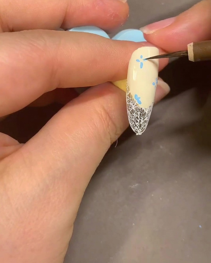 Ein Aquarell-Pinsel verblendet die blauen Marker-Blütenblätter auf einem Nagel mit Alkohol für einen rauchigen Look.