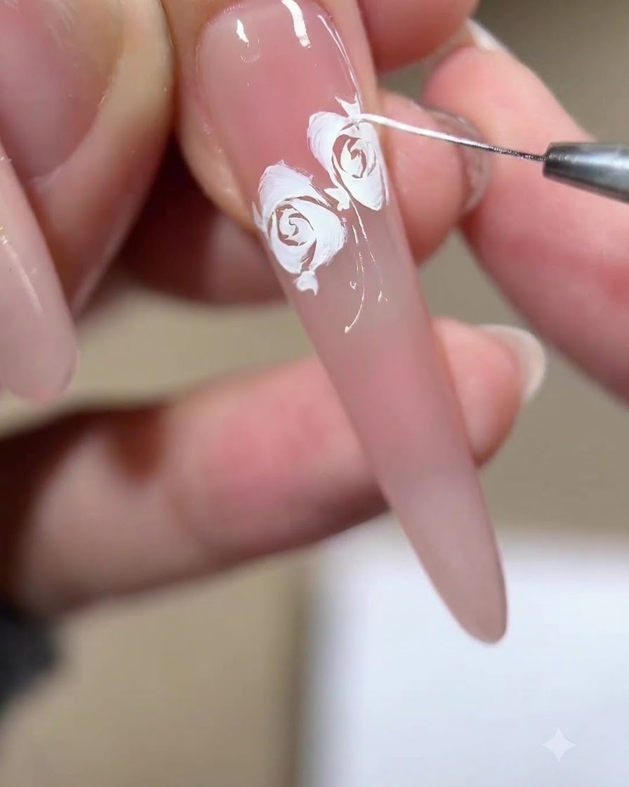 Nahaufnahme eines Linienpinsels, der feine weiße Fransen und Fragmente um die Ränder eines fertigen Rosendesigns zieht.