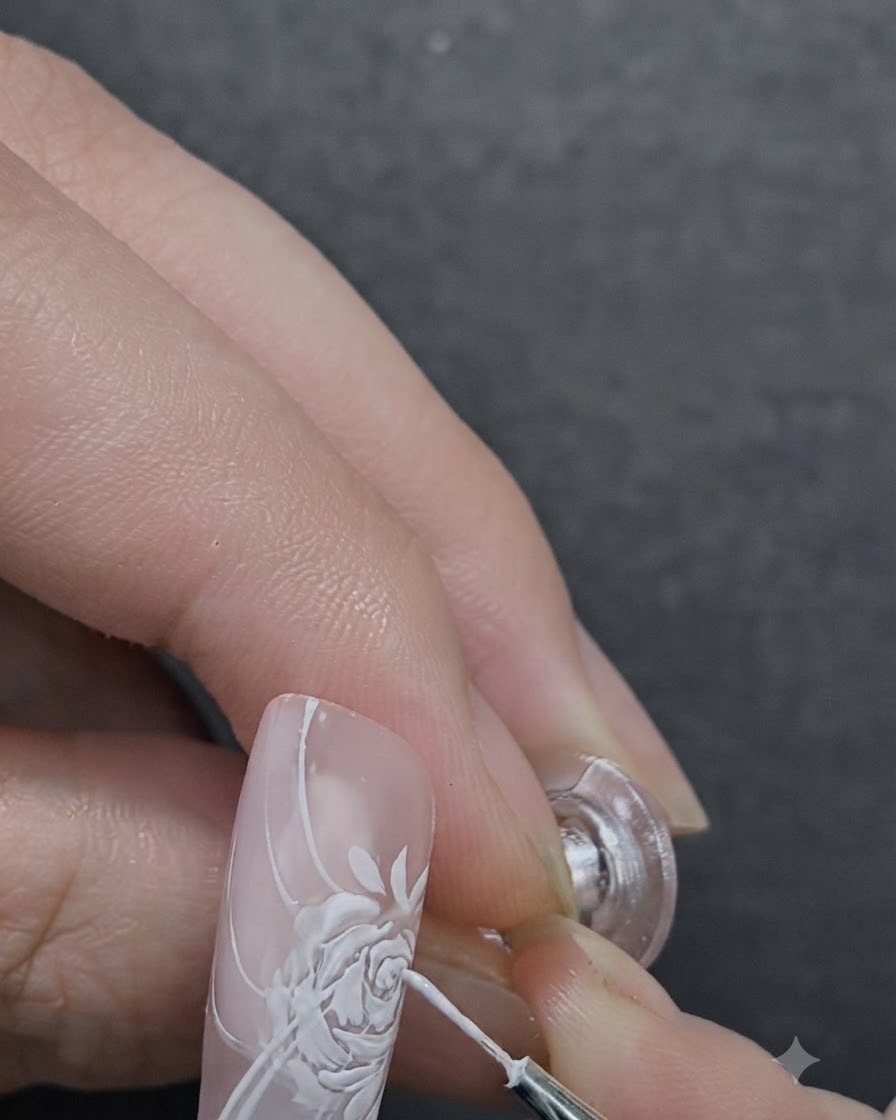 Ein Nageldesigner trägt mit einem Detailpinsel 3D-Modelliergel auf die Mitte einer gemalten Rose auf.