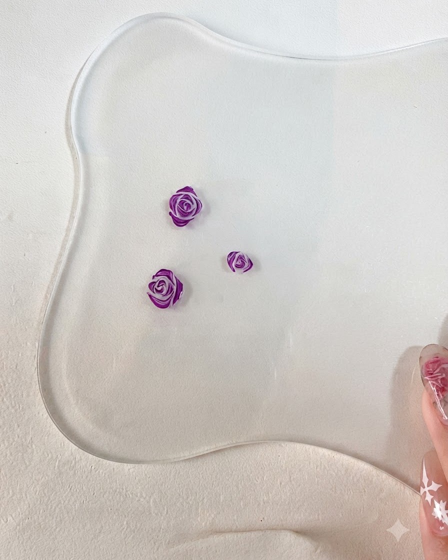 Eine Nahaufnahme eines feinen Nail-Art-Pinsels, der detaillierte dunkelviolette Umrisse auf die Kanten der modellierten 3D-Rosenblblätter zeichnet.