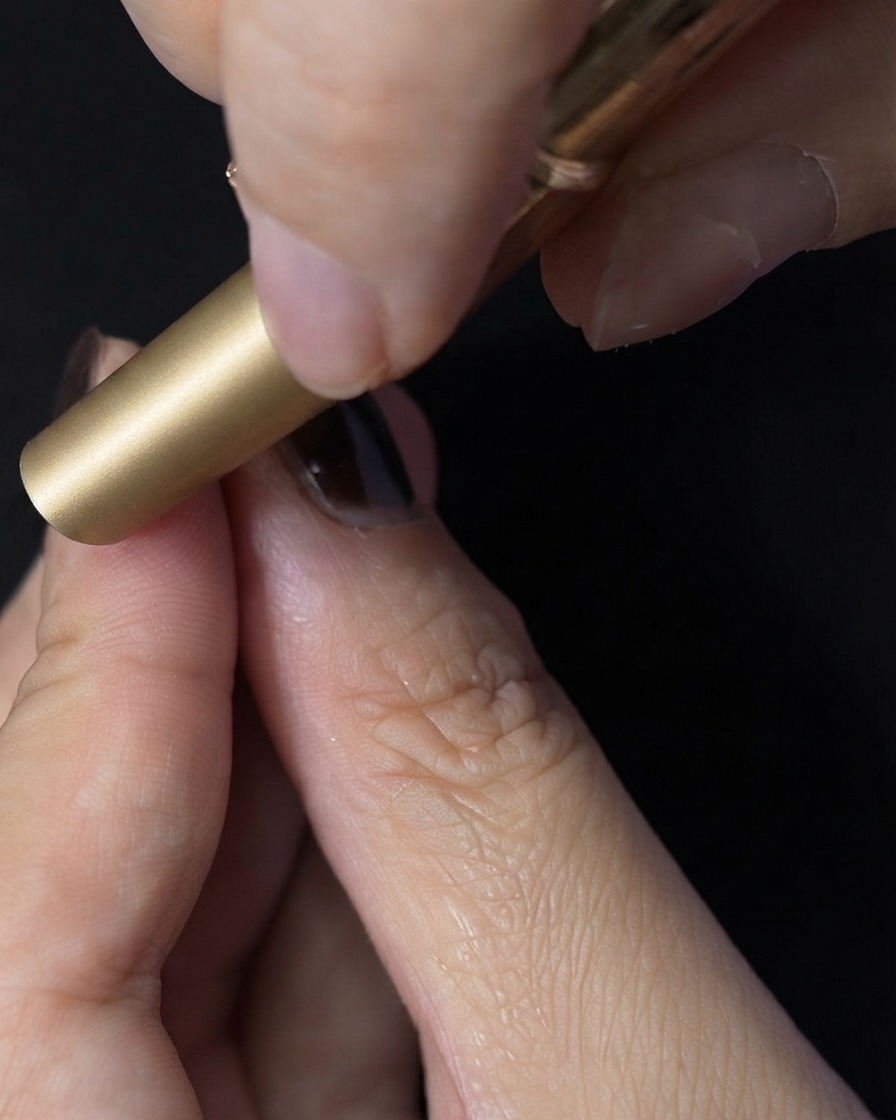 Ein Fingernagel wird zum Aushärten des Top Coats in eine Mini-UV/LED-Lampe gelegt.