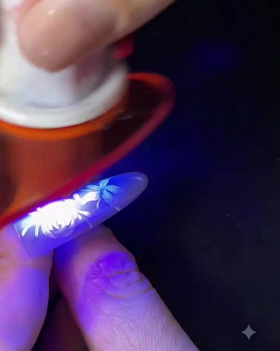 Ein Finger mit fertiger weißer floraler Nail Art härtet unter einer kleinen blauen UV/LED-Nagellampe aus.