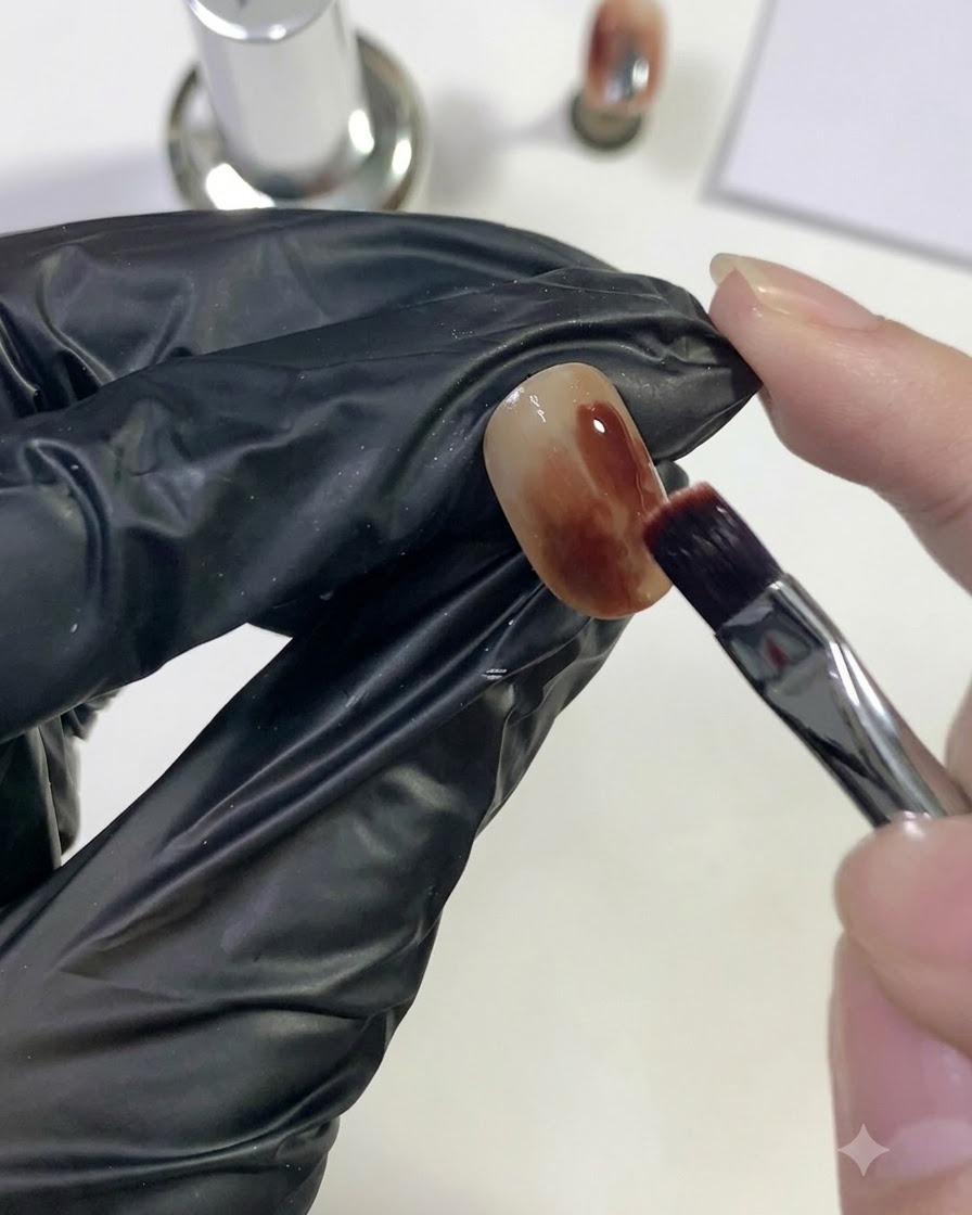 Ein Pinsel trägt tiefrotes Gel auf einen begrenzten Bereich des Nagels auf.