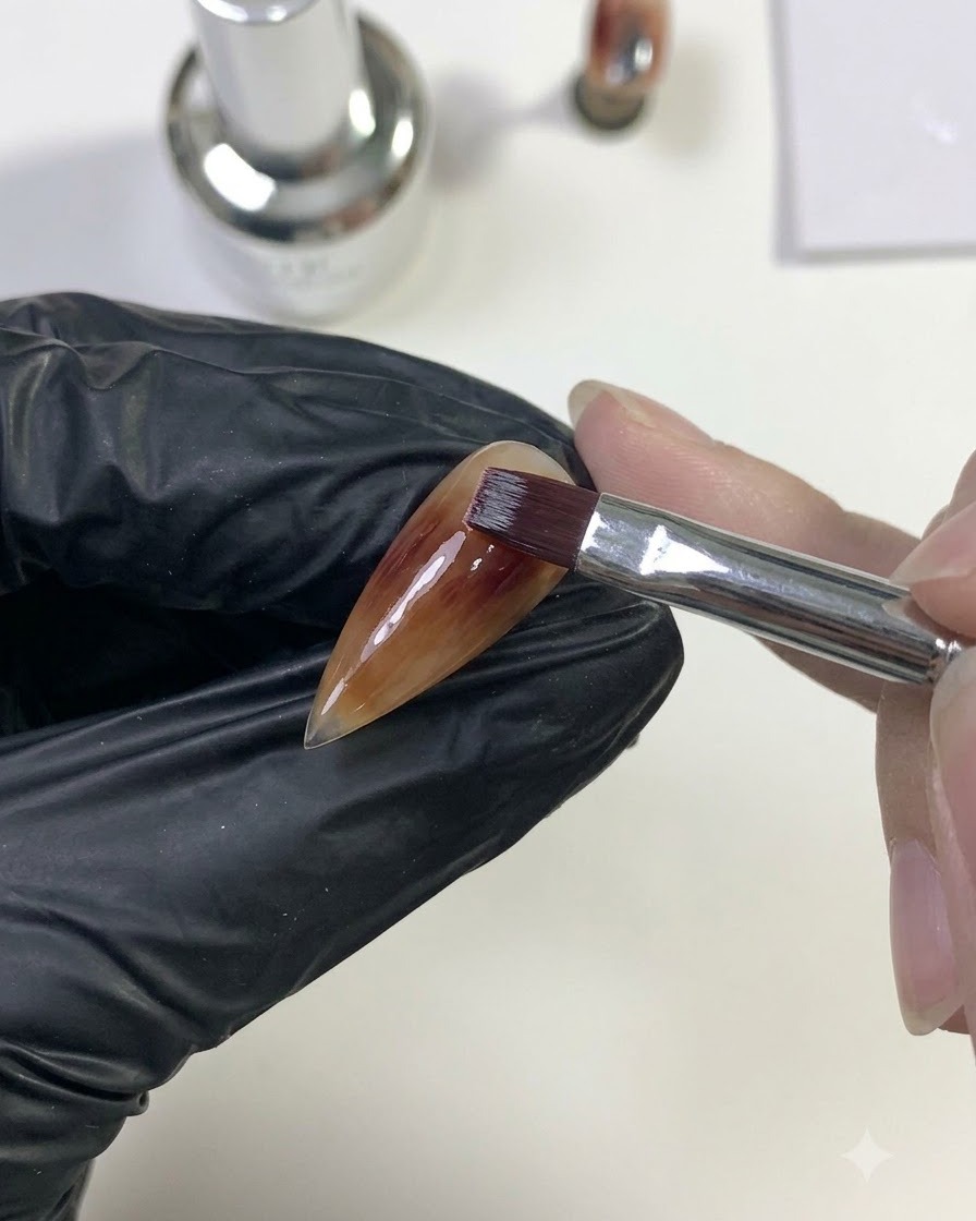 Ein Pinsel verblendet tiefrotes Gel nach außen, um mit der darunter liegenden Karamell-Basisschicht zu verschmelzen.
